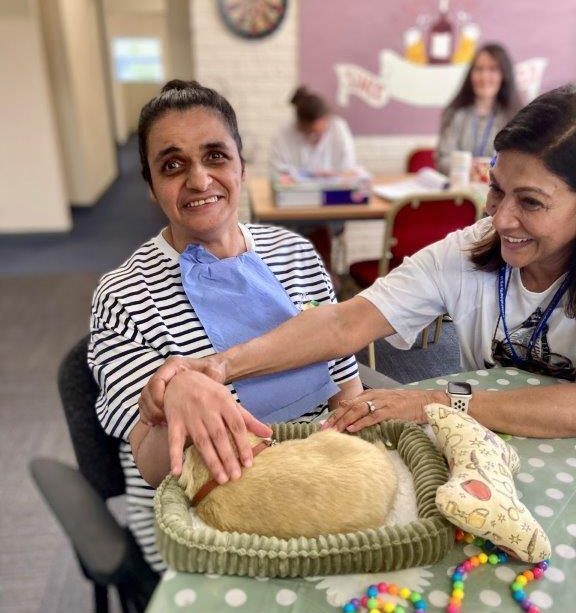 A woman being supported while stroking a therapy dog