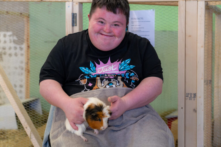 Man smiling while holding a guinea pig during an animal care session