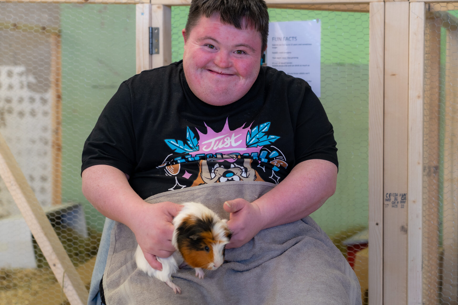 Man smiling while holding a guinea pig during an animal care session