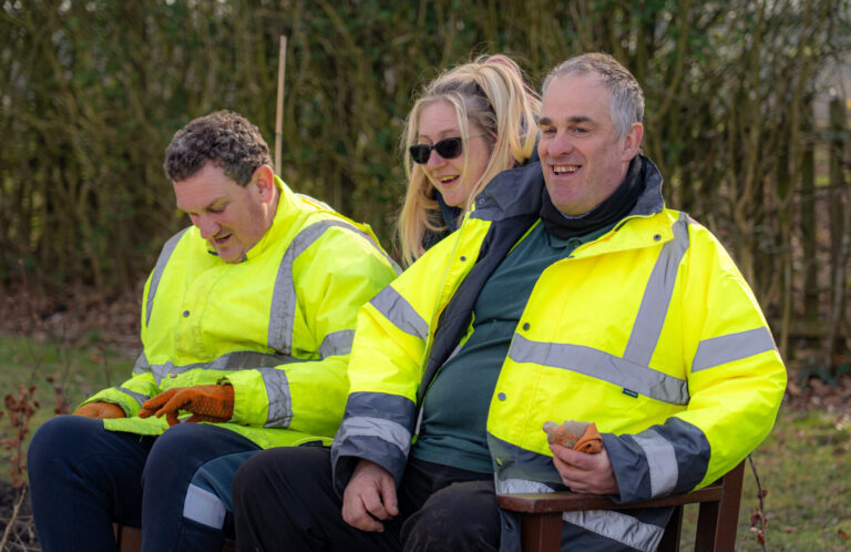 Three happy people sitting in high-vis jackets