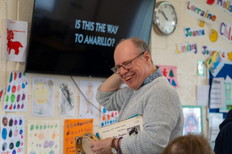 Man with glasses holding vinyls while laughing