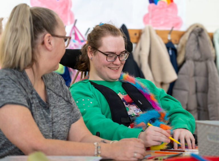 Two women smiling while drawing