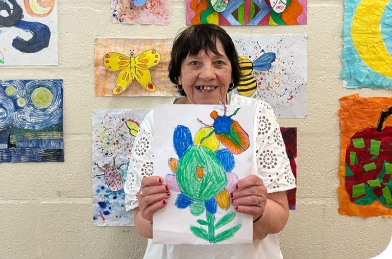 a woman holding a piece of paper with a drawing on it