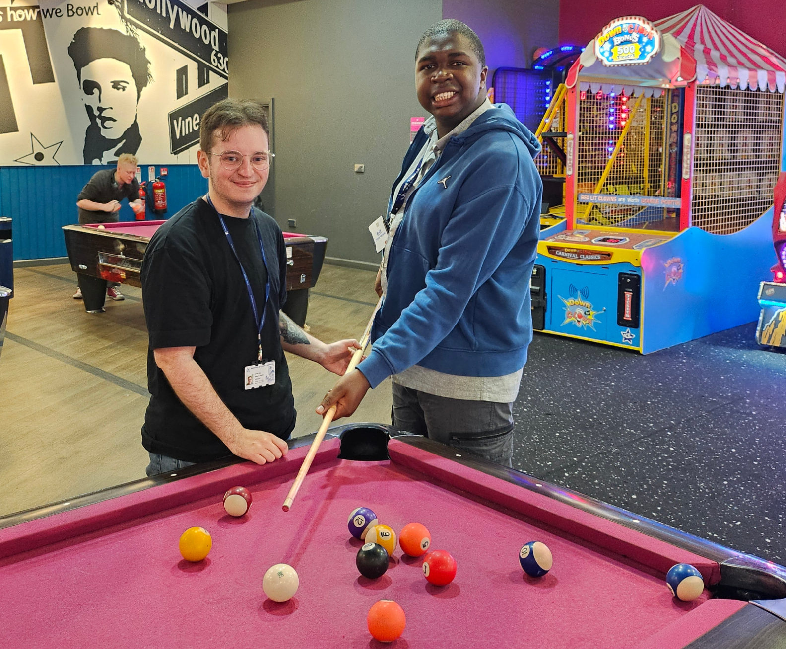 Two adults smiling while playing pool in a leisure centre