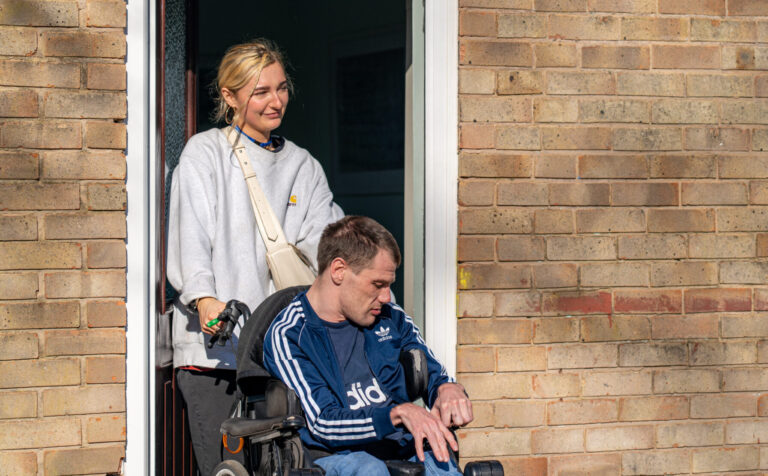 Support worker helping an adult in a wheelchair move through a doorway