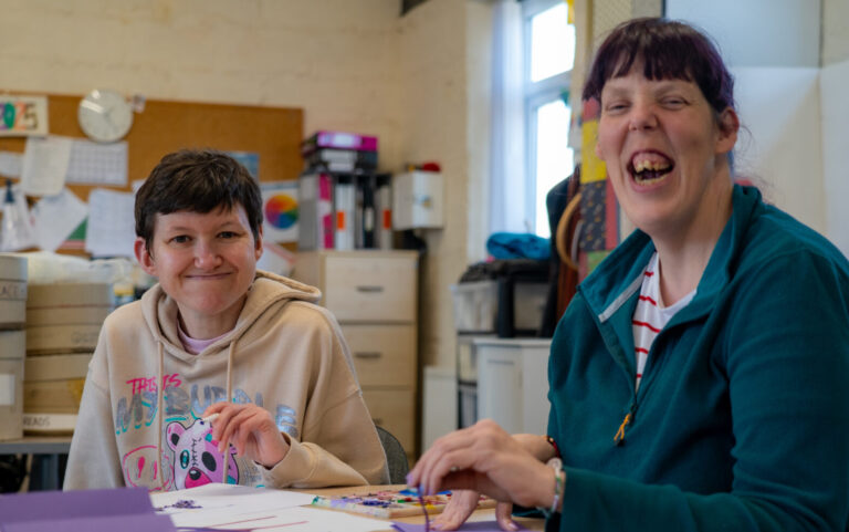 Two women laughing while painting