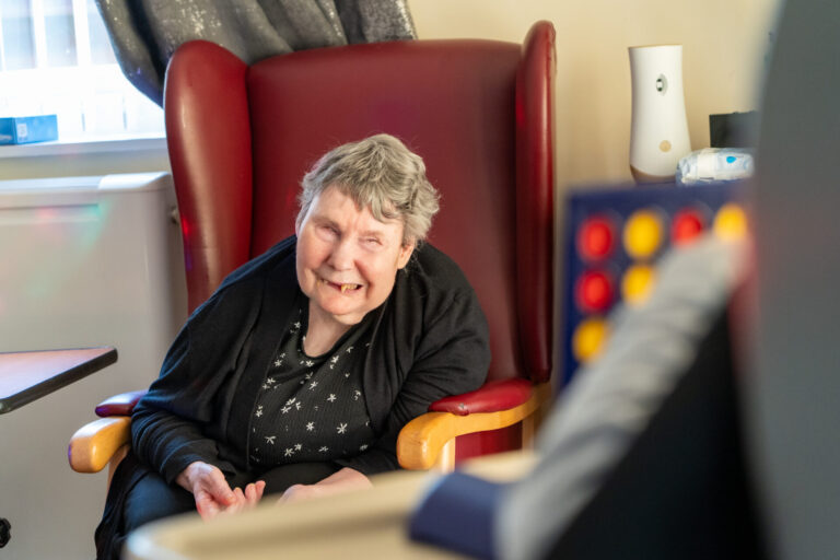 a woman sitting in a chair, smiling to the camera