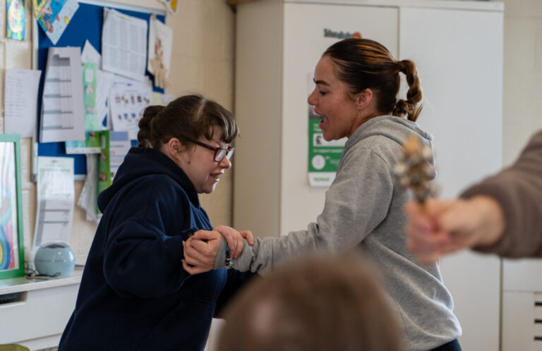 Two women collaborating, holding each others' arms