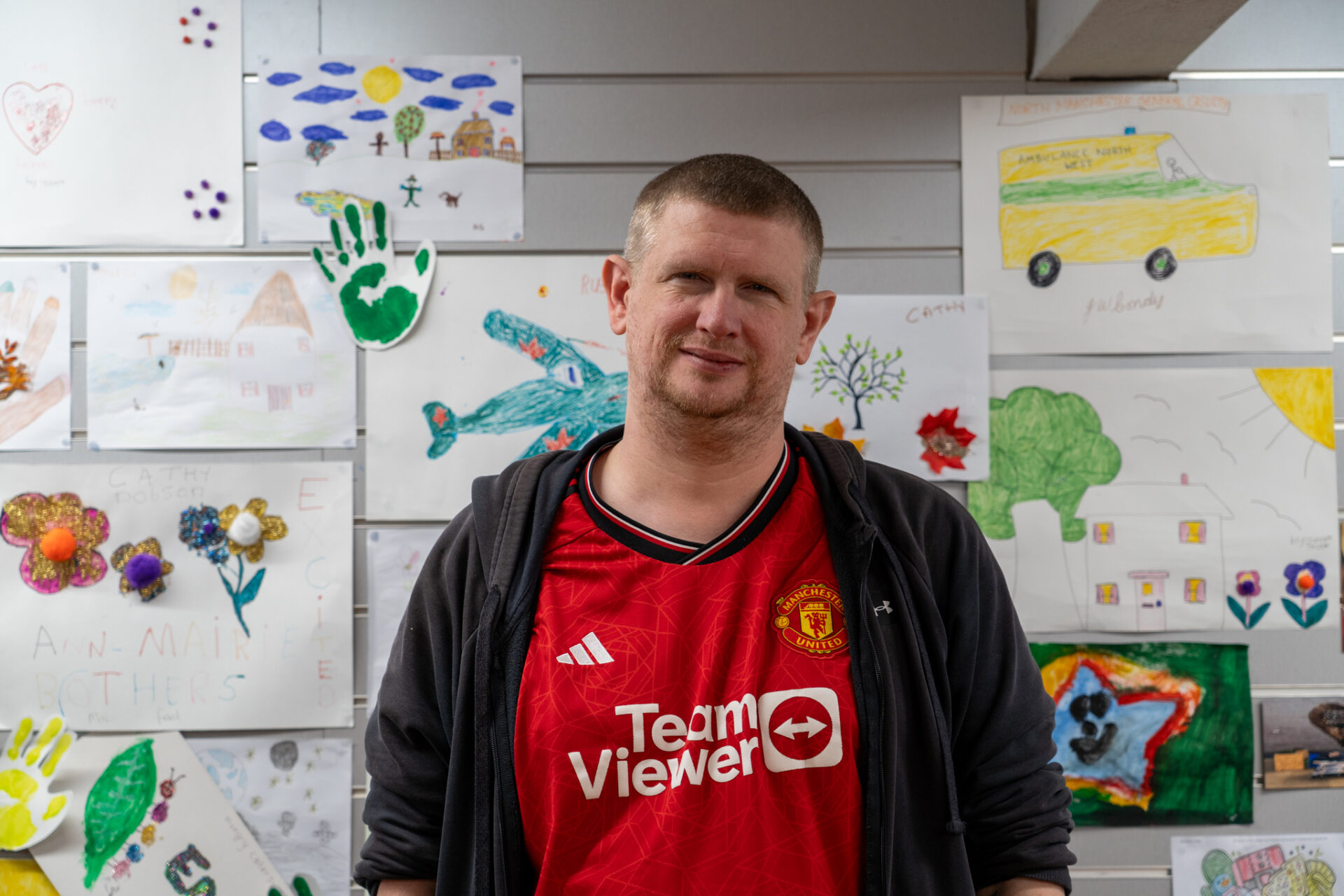 Arthur stood in front of wall of drawings