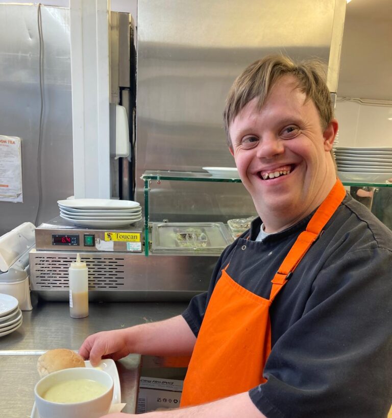Man at Roccoco smiling while holding a bowl of soup